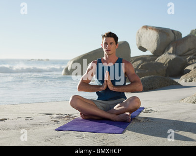 Junger Mann beim Yoga am Strand Stockfoto