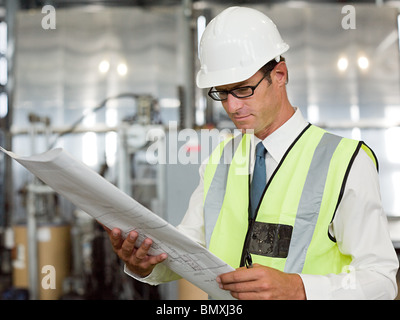 Reifer Mann mit Blaupause in Fabrik Stockfoto