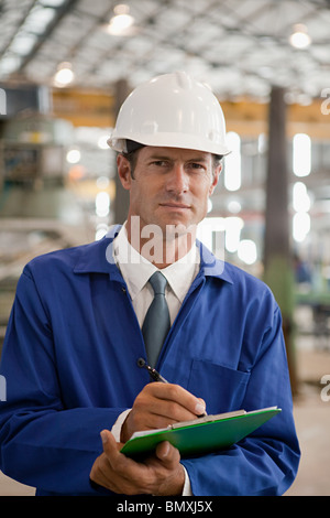 Reifer Mann mit Zwischenablage in Fabrik Stockfoto