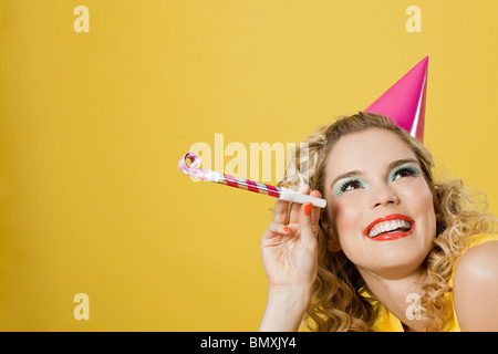 Junge Frau trägt Partyhut mit Partei-Gebläse Stockfoto