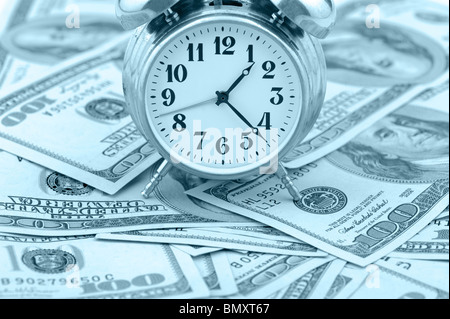 Zeit - Geld. Business-Konzept. Analoge Uhr auf einem Haufen Papier-Dollar. Blauton Stockfoto