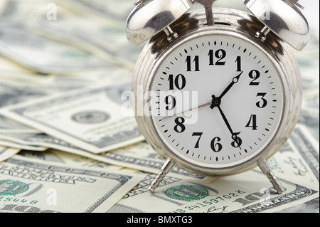 Zeit - Geld. Business-Konzept. Analoge Uhr auf einem Haufen Papier-Dollar Stockfoto