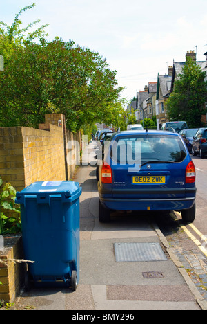 Autos und Wheelie Lagerplätze auf dem Fußweg geparkt sind ein Hindernis für Fußgänger in Oxford. Stockfoto