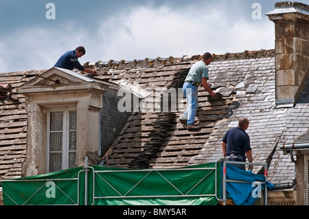 Arbeitnehmer auf Stadthaus Dach entfernen alte Schiefer / keine Sicherheitseinrichtungen oder Helme - Frankreich. Stockfoto