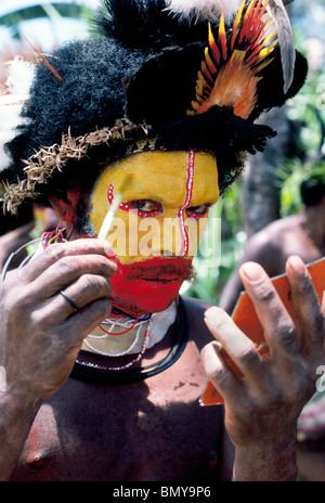 Ein Huli Wigman malt sein Gesicht in leuchtenden Farben für eine traditionelle Sing-Sing-Zeremonie bei Tari im südlichen Hochland von Papua-Neuguinea (PNG). Stockfoto