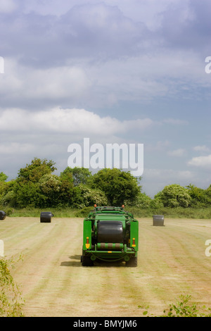 Heu-Ballenpresse in einem Feld auf einem Bauernhof in Irland Stockfoto