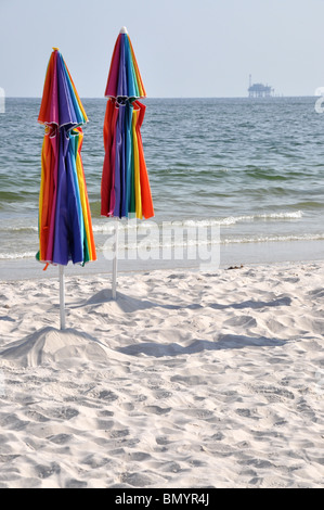 Verlassenen Strand mit geschlossenen Schirmen. Off Shore Bohrinsel im Hintergrund. Stockfoto