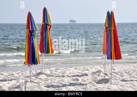 Verlassenen Strand mit geschlossenen Schirmen. Off Shore Bohrinsel im Hintergrund. Stockfoto