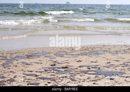 Ölpest am Strand mit off Shore Bohrinsel im Hintergrund. Stockfoto