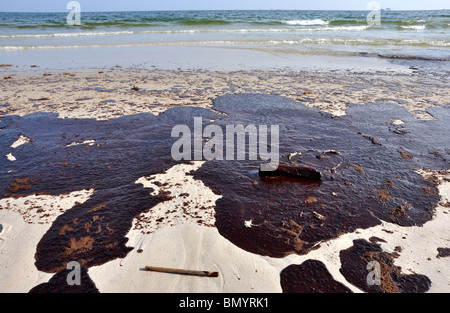 Ölpest am Strand mit off Shore Bohrinsel im Hintergrund. Stockfoto