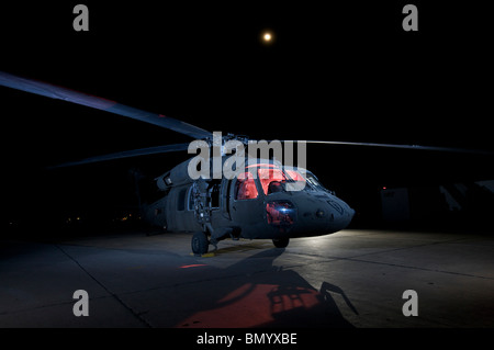 Ein UH-60 Black Hawk-Hubschrauber durch mehrere Blitzgeräte bei Vollmond beleuchtet. Stockfoto