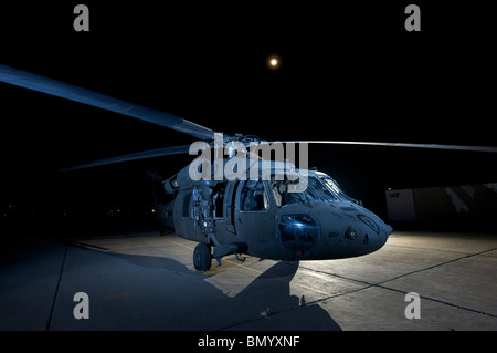 Ein UH-60 Black Hawk-Hubschrauber durch mehrere Blitzgeräte bei Vollmond beleuchtet. Stockfoto