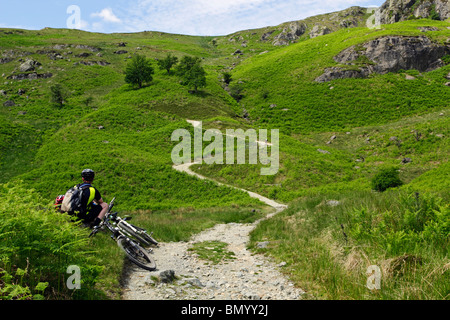 Ein Mountainbiker mit Blick auf den Weg bis zum Joch in der Nähe von Kentmere im Lake District, Cumbria, England. Stockfoto