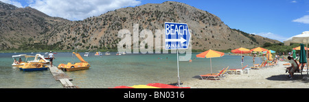 Der Kiesstrand am See Kournas, Kreta und eine Anlegestelle für die Tretboote für Touristen. Stockfoto