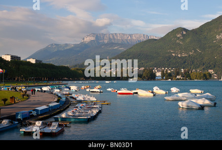 Boote vertäut entlang der Küstenlinie und der Promenade des Lac d ' Annecy in der Bergstadt Annecy, Frankreich Stockfoto