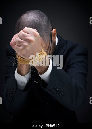 Ein Mann in einem Anzug ist seine gefesselten Händen anheben. Stockfoto