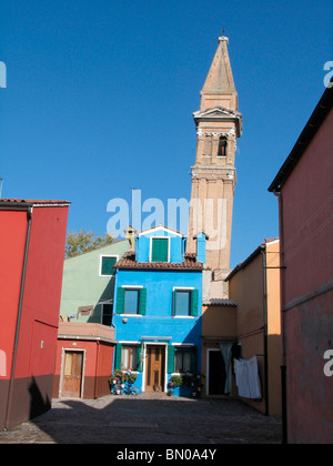 Bunte Häuser und ein hoher Glockenturm erheben sich vor dem klaren blauen Himmel in Burano, Venedig. Italien Stockfoto