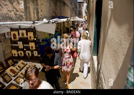 Touristen gehen und Einkaufen in einer schmalen Seitenstraße am Sonntagsmarkt in der Altstadt von Pollença, Mallorca 2010 Stockfoto