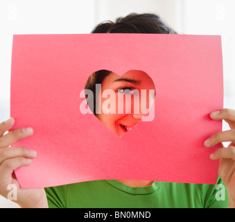 Hispanic Frau auf der Suche durch herzförmige Loch Stockfoto