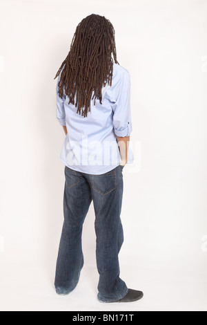 Junger Mann mit Dreadlocks stehend, Hände in den Taschen zurück zu Kamera Stockfoto