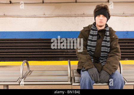 Ein junger Mann sitzt in einer unterirdischen u-Bahn-Station. Stockfoto