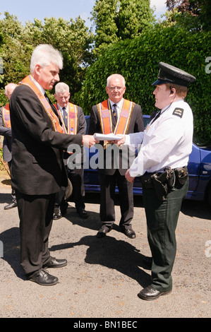 27. Juni 2010, Drumcree Kirche. Stellvertretende WM Nigel Dawson übergibt eine 11 Bar 1' Form ein Polizei-Offizier Stockfoto