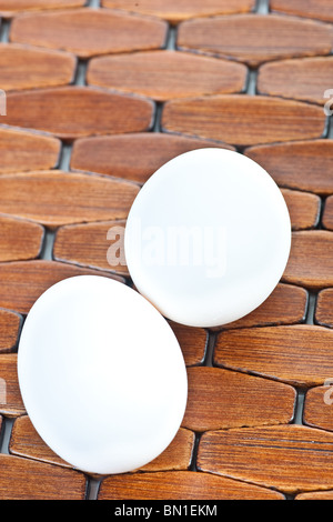 Nahaufnahme, zwei weiße Eier auf eine hölzerne gefliesten Platzdeckchen. Stockfoto