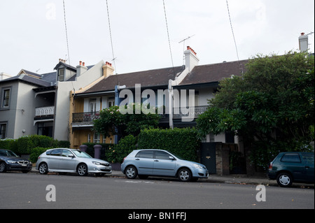 Reihenhäuser mit Autos geparkt auf der Straße vor ihnen im Stadtteil Sydney von Paddington. Stockfoto