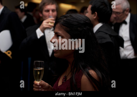 Eine junge Frau trinkt Champagner bei einer offiziellen Veranstaltung an einem College in Oxford. Stockfoto