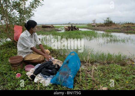 Ein Dorfbewohner untersucht die Verwüstung durch den Zyklon Nargis AS In einem überfluteten ländlichen Gebiet in Myanmar wäscht sie Kleidung Stockfoto