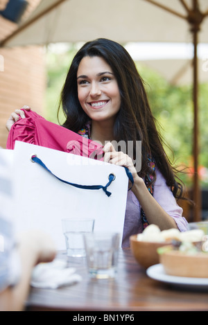 Frau sitzt im Café mit Freund, zeigt Kleidung Shopping bag Stockfoto