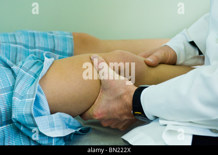 Arzt untersuchen Patienten Bein und Knie Stockfoto