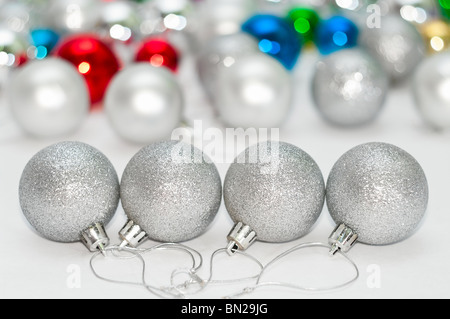 Vier graue Weihnachtskugeln auf Vorder- und vielen farbigen Kugeln auf Hintergrund Stockfoto