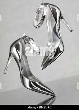 Stilvolle glänzend silberne Stiletto high Heel Schuhe fallen auf Metalloberfläche Stockfoto