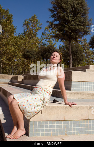 Frau lehnt sich zurück und Sonnenbaden mit geschlossenen Augen Stockfoto