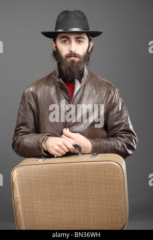 Reisende mit Koffer, gekleidet in Jacke und Hut Stockfoto