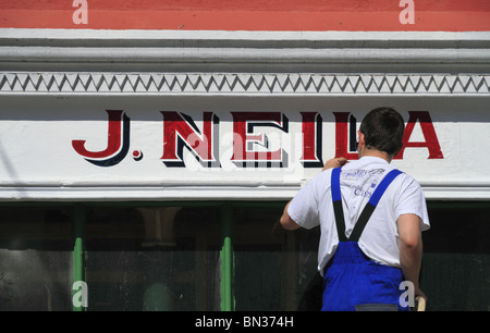 Ein Zeichen Schriftsteller bei der Arbeit auf eine Ladenfront in der Grafschaft Limerick, Rep of Ireland. Stockfoto