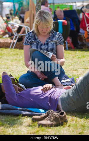 Zwei junge Frauen, die lesen, entspannen und dösen im Schatten bei Hay Festival 2010 Hay on Wye Powys Wales UK Stockfoto