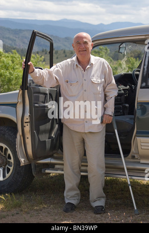 Reife Mann mit Spazierstock stehend durch sein Auto in spanischen Berge deaktiviert Stockfoto