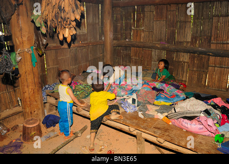 Kinder spielen auf einem Bett in einem Haus von einem Hmong Dorf Mae Hong Son, Nord-Thailand, Asien Stockfoto