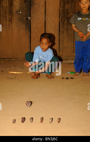 Young Black Lahu Jungs spielen mit Steinen auf dem Boden, hill Tribe von Mae Hong Son, Nord-Thailand, Asien Stockfoto