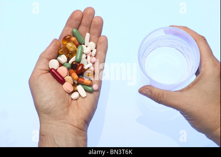 Nahaufnahme der Person, die Hände halten Glas Wasser und Medikamente Stockfoto