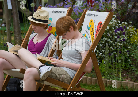 Junge Frauen lesen von Büchern saß in Liegestühlen neben Garten bei Hay Festival 2010 Hay on Wye Powys Wales UK Stockfoto