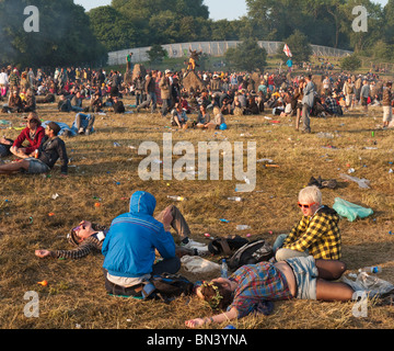 Menschen versammeln sich um den Steinkreis bei Sonnenaufgang nach einer Partynacht auf dem Glastonbury Festival in Somerset, Großbritannien Stockfoto