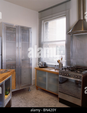 Große Metall Schrank mit Milchglas-Türen in moderne Küche mit Edelstahl-Herd und Lattenrost Metall blind Stockfotografie