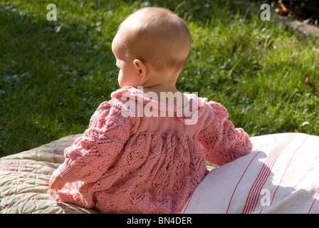 Rückseitige Ansicht von einem Babymädchen sitzen im Garten Stockfoto