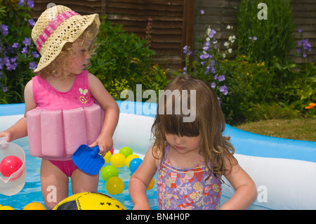 Zwei junge weibliche Kinder spielen In A Paddling pool