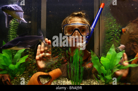 Ein 9 Jahres altes Mädchen tragen einen Schnorchel und Maske schaut die Fische in ihrem Aquarium. Stockfoto