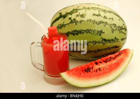 Eine vollständige Wassermelone mit Glas Melonensaft und geschnittene Scheibe zeigt rote wässrige Fruchtfleisch und schwarzen Samen; Pune; Maharashtra; Indien Stockfoto