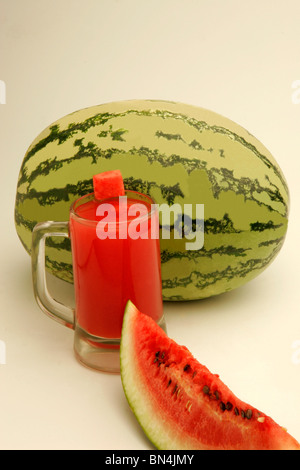 Eine vollständige Wassermelone und eine geschnittene Scheibe mit Fruchtfleisch und schwarzen Samen mit Glas Melonensaft; Pune;  Maharashtra; Indien Stockfoto